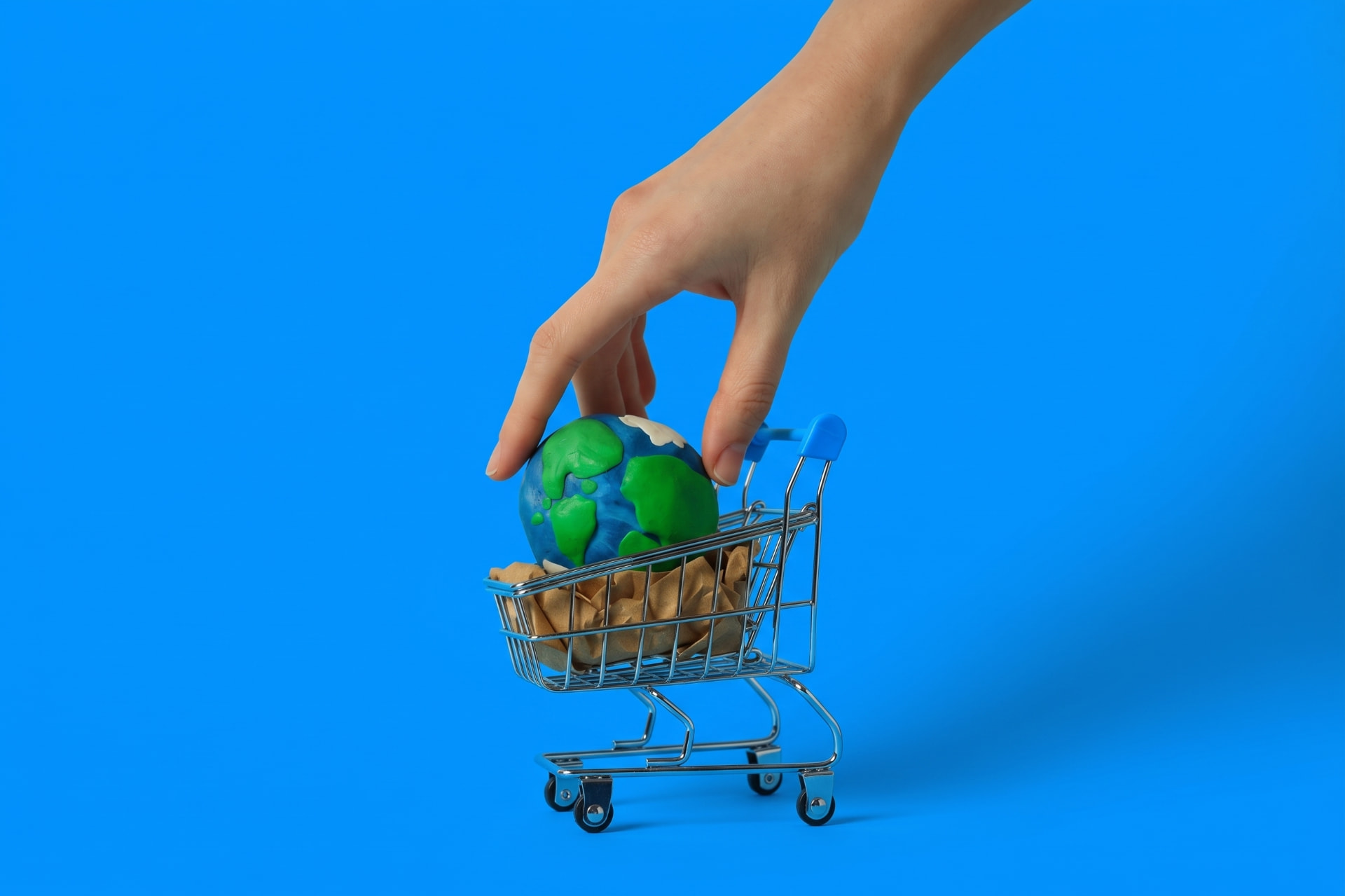 Mano colocando un globo dentro de un carrito de compras